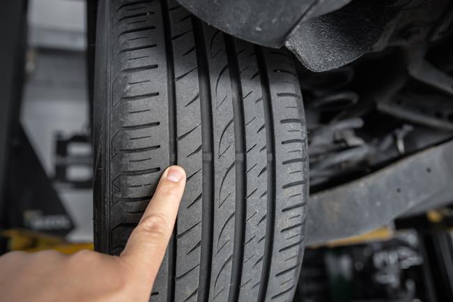 mechanik wskazujący na uszkodzony bieżnik w oponie